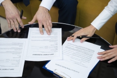 high-angle-hands-signing-documents-scaled